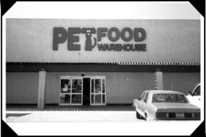 A car parked in front of a pet food warehouse.