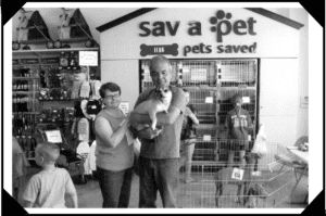 A man and woman holding a baby in front of a pet store.