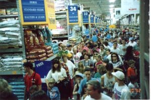 A crowd of people in a store with many signs.